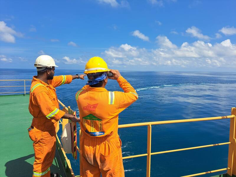 Two crew members in safety gear on a ship's deck