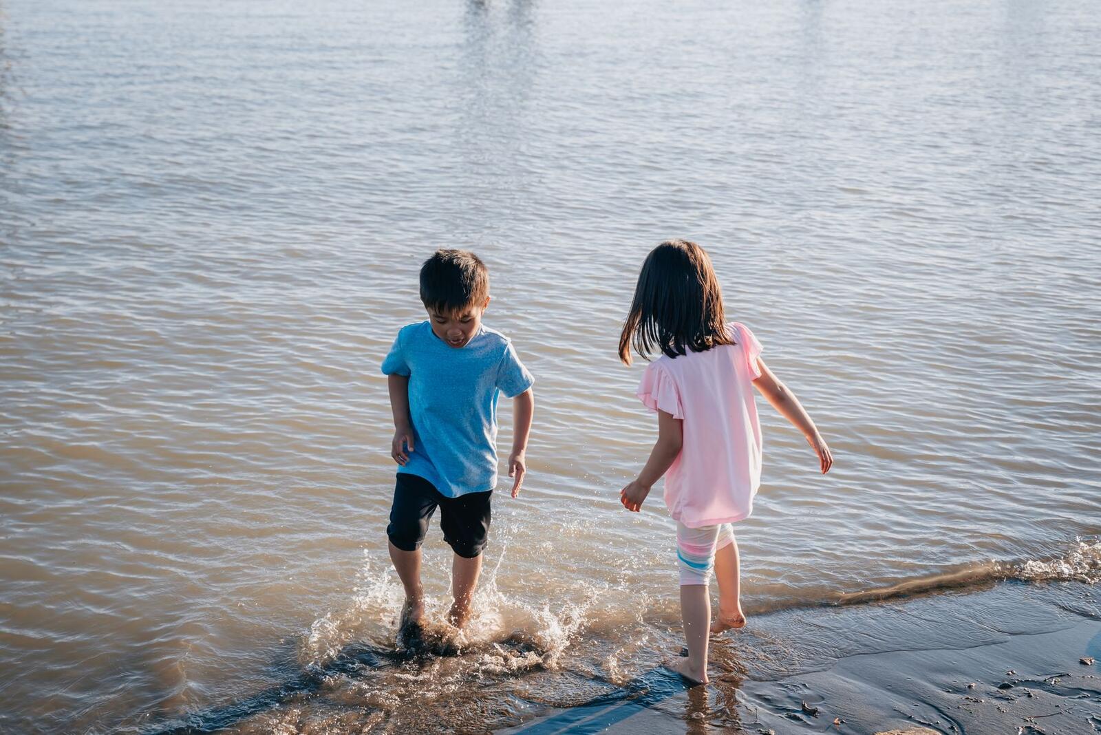 Two children running through shallow water on a beach