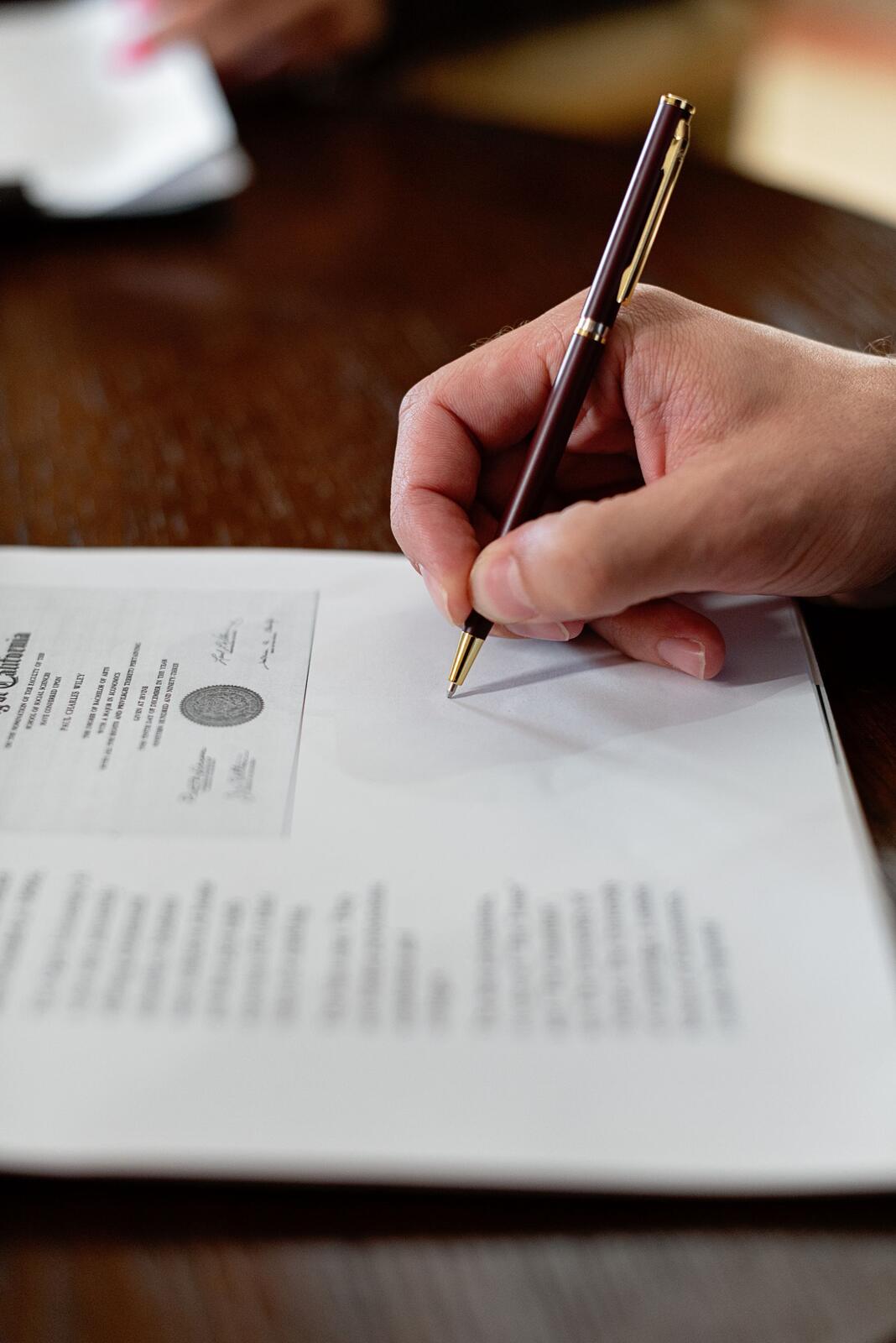 A hand signing a document with a pen